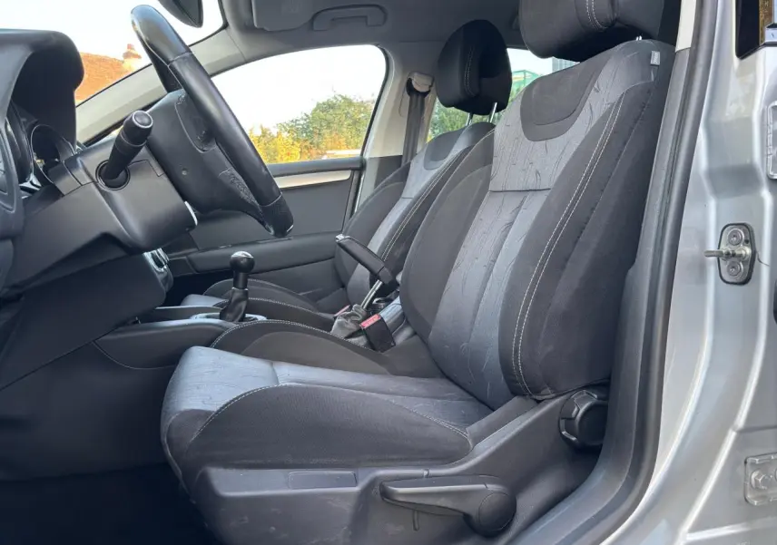 Vue intérieure côté conducteur de la Citroën C4 gris clair 2012, montrant sièges tissu noirs et levier de vitesse manuel.