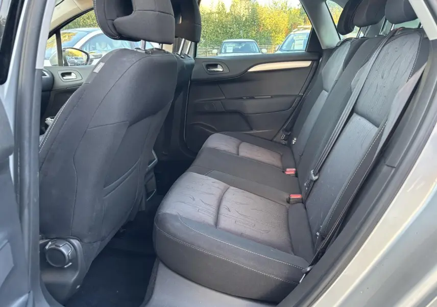 Vue intérieure côté droit des sièges arrière en tissu gris foncé d'une Citroën C4 gris clair de 2012.