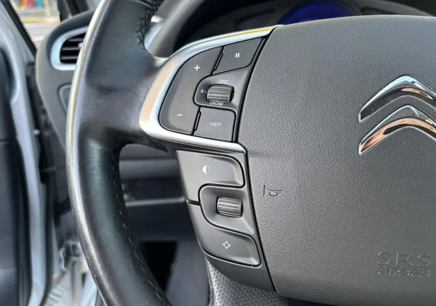 Gros plan sur le volant noir de la Citroën C4 gris clair, montrant les commandes de régulateur et limiteur de vitesse.