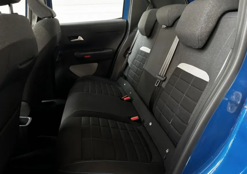 Vue intérieure côté droit des sièges arrière noirs et gris de la Citroën C3 2025 avec porte bleue ouverte.