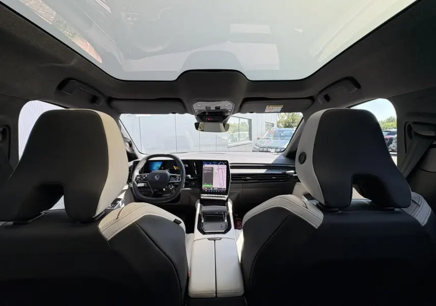 Vue intérieure arrière du Renault Espace 2025 bleu nocturne, avec toit panoramique et écran tactile central visible.