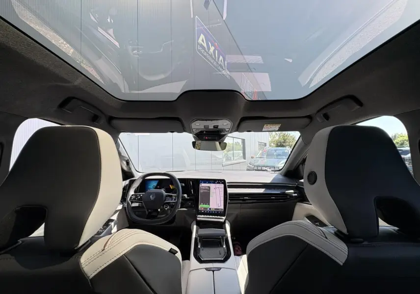 Vue intérieure avant du Renault Espace 2025 avec toit panoramique, sellerie gris sable clair et tableau de bord moderne.