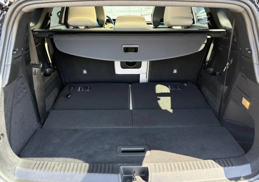 Vue arrière du coffre spacieux du Renault Espace VI hybride, banquette arrière rabattue et cache-bagages déployé.