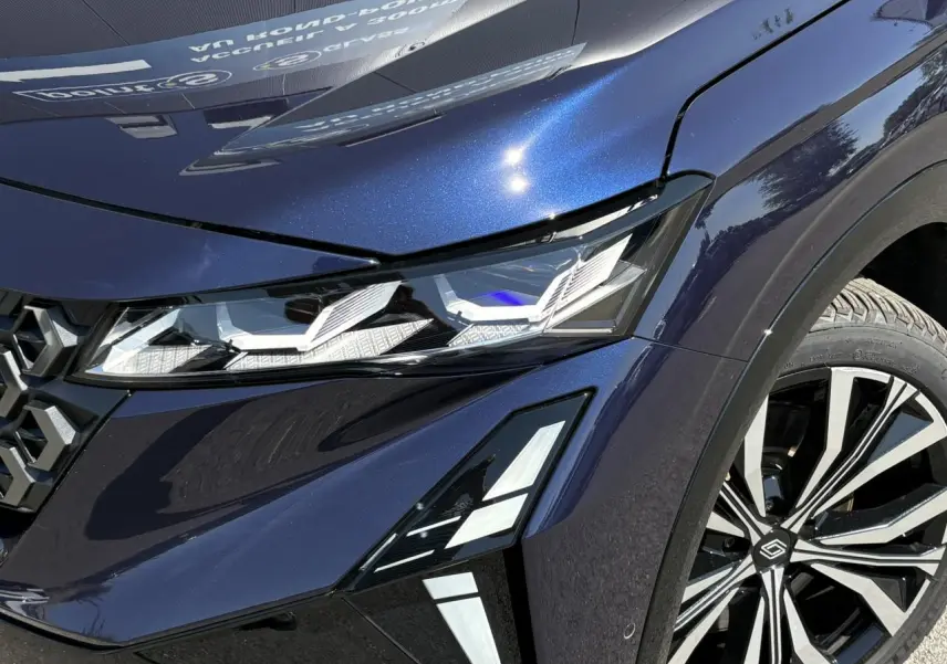 Gros plan sur l'avant droit bleu nocturne du Renault Espace 2025, mettant en valeur le phare LED matrix et la jante alliage 20 pouces.