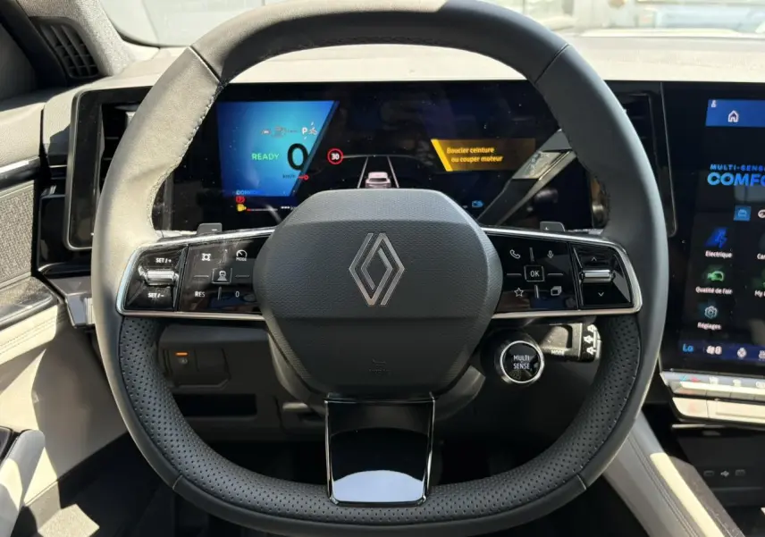 Vue frontale du volant noir perforé de la Renault Espace 2025 avec affichage numérique et commandes intégrées.