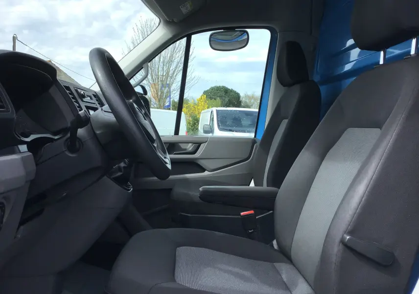 Vue intérieure côté conducteur du Volkswagen Crafter Châssis Cabine bleu 2017, sièges gris et volant noir visibles.