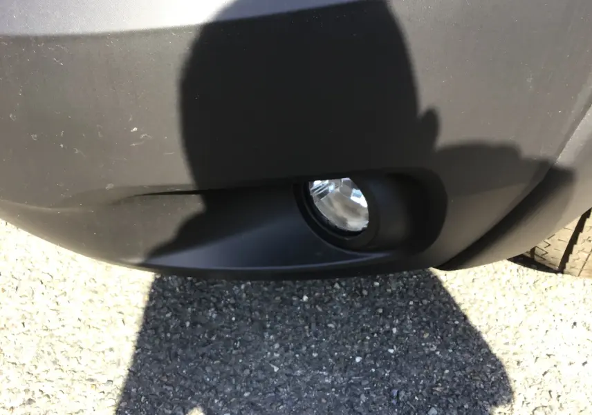 Gros plan sur le feu antibrouillard avant droit du FIAT Ducato Chassis Benne blanc, avec ombre portée sur le pare-chocs noir.