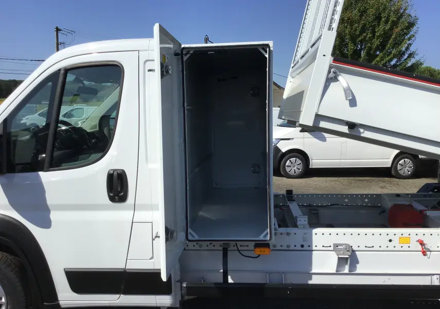 Vue latérale gauche du FIAT Ducato Chassis Benne blanc 2023 avec coffre ouvert et benne relevée en acier.