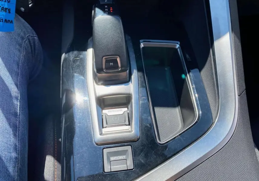 Le levier de vitesse automatique et bouton sport du Peugeot 5008 gris clair vus de dessus dans l'habitacle.