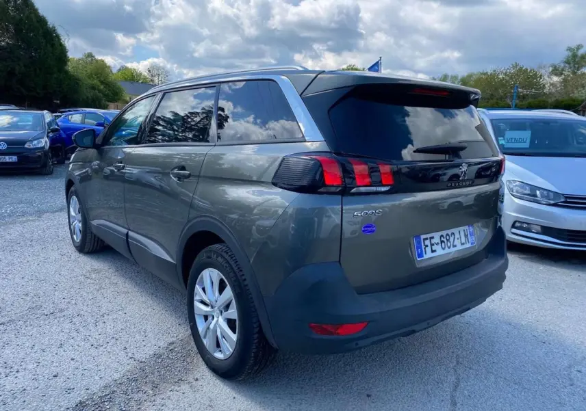 Peugeot 5008 gris clair vue 3/4 arrière droit, vitres surteintées et feux arrière à griffes rouges.