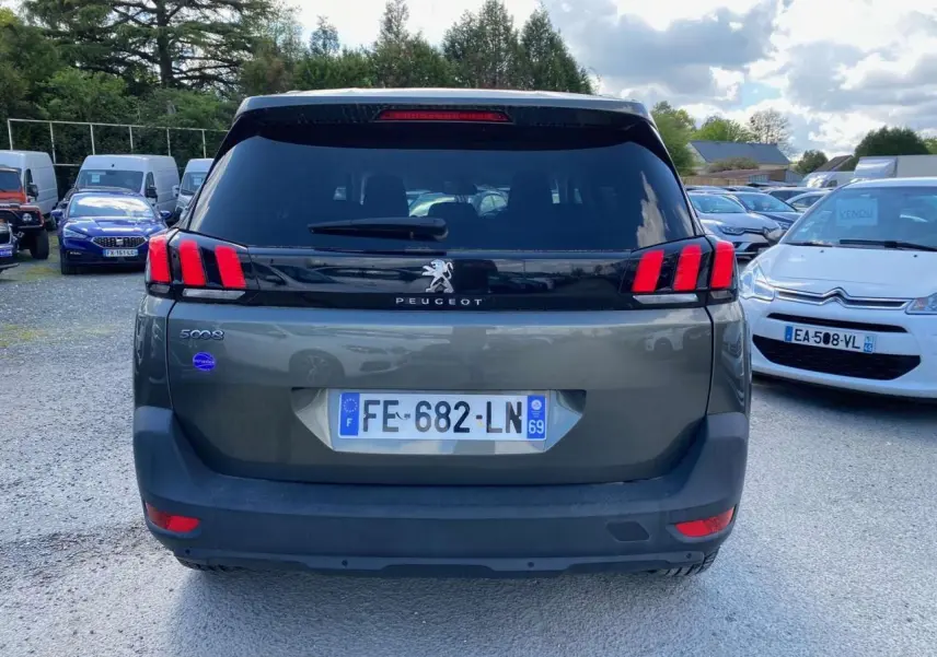 Vue arrière d'un Peugeot 5008 gris clair avec feux arrière à griffes rouges et lunette arrière surteintée.