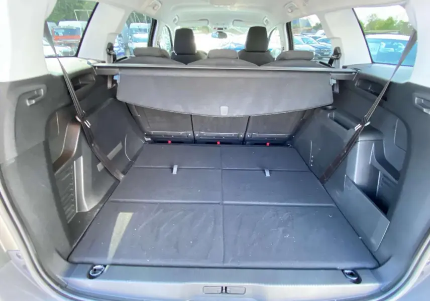 Coffre ouvert du Peugeot 5008 gris clair, montrant les sièges arrière rabattus et la tablette cache-bagages déployée.
