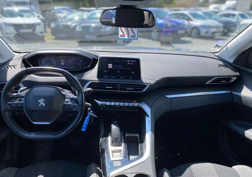 Vue intérieure avant du Peugeot 5008 gris clair, avec tableau de bord moderne et écran tactile central.
