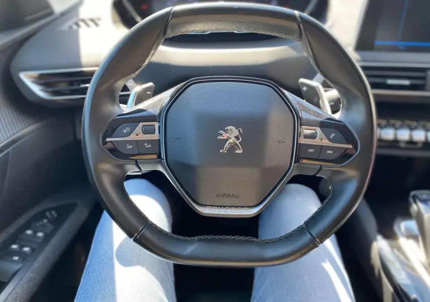 Vue rapprochée du volant cuir noir du Peugeot 5008 2019 avec commandes intégrées et logo lion central.