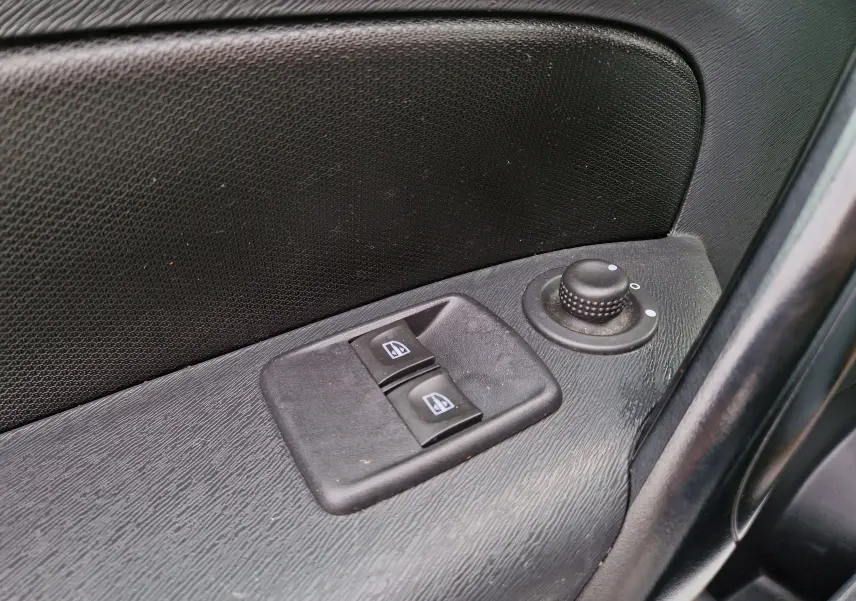 Gros plan sur les commandes électriques des vitres et le réglage des rétroviseurs côté conducteur du Renault Kangoo blanc 2020.