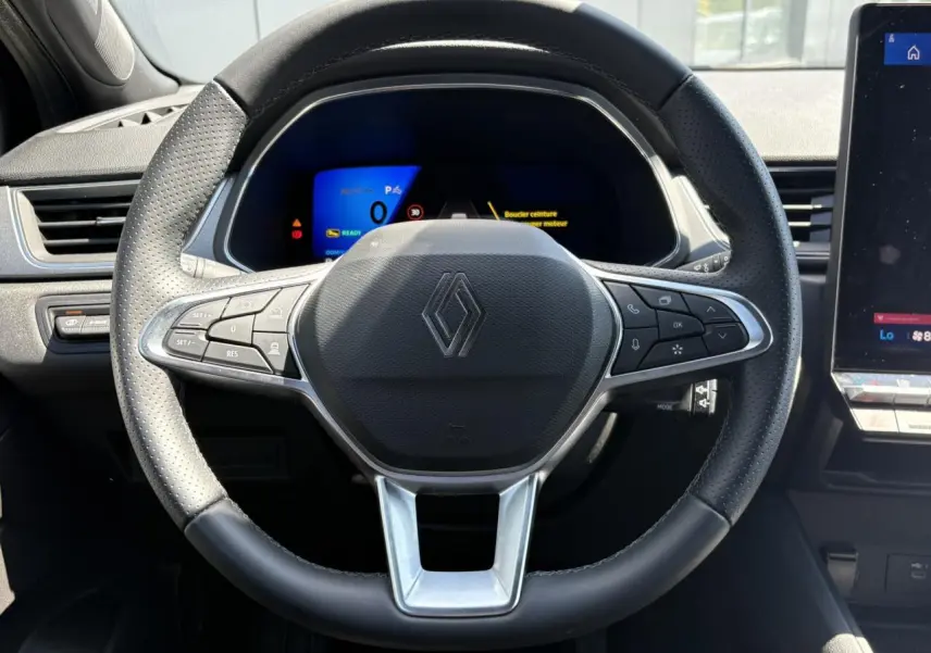 Vue frontale du volant noir perforé de la Renault SYMBIOZ 2025 avec tableau de bord numérique et écran tactile latéral.