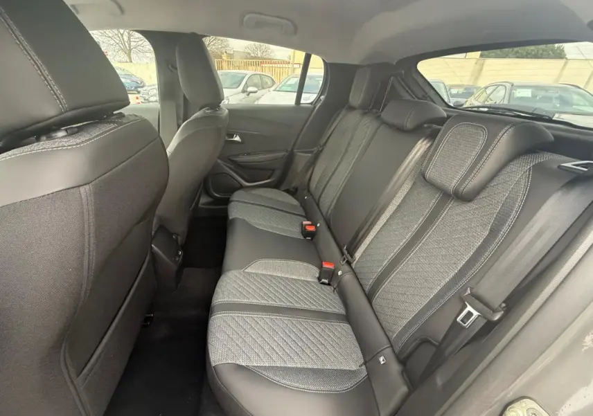 Vue intérieure arrière côté droit montrant les sièges arrière gris avec surpiqûres et ceintures de sécurité de la Peugeot 208 Hybrid 145 Allure 2025.