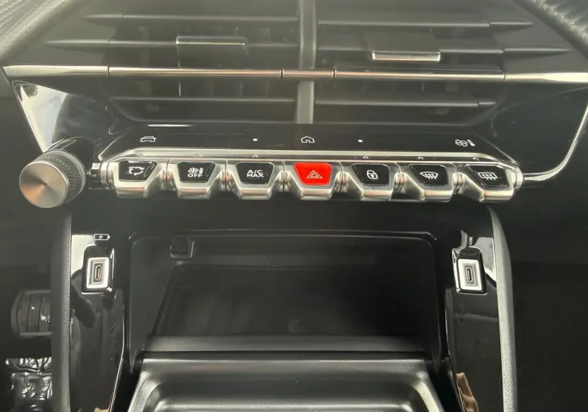 Vue rapprochée du tableau de bord de la Peugeot 208 Hybrid 145 Allure 2025, avec boutons de commande et finition noire brillante.