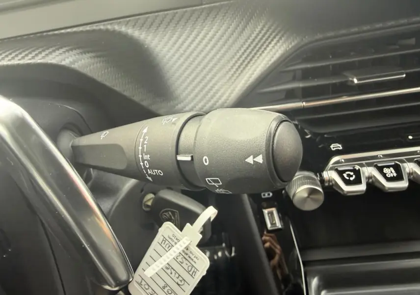 Gros plan sur la commande d’essuie-glace et la partie droite du tableau de bord carbone d’une Peugeot 208 gris 2025.