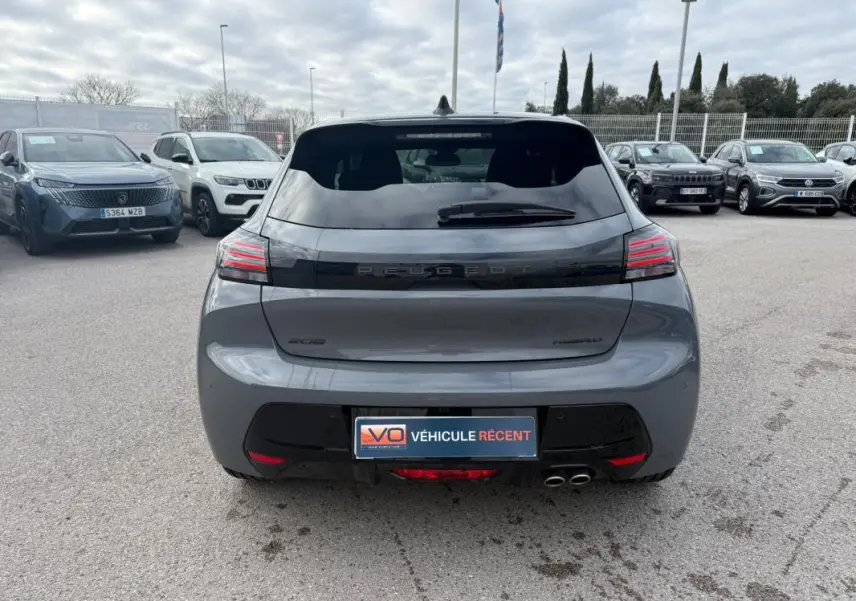 Vue arrière d'une Peugeot 208 Hybrid 145 gris métallisé, avec feux arrière LED et double sortie d'échappement visible.
