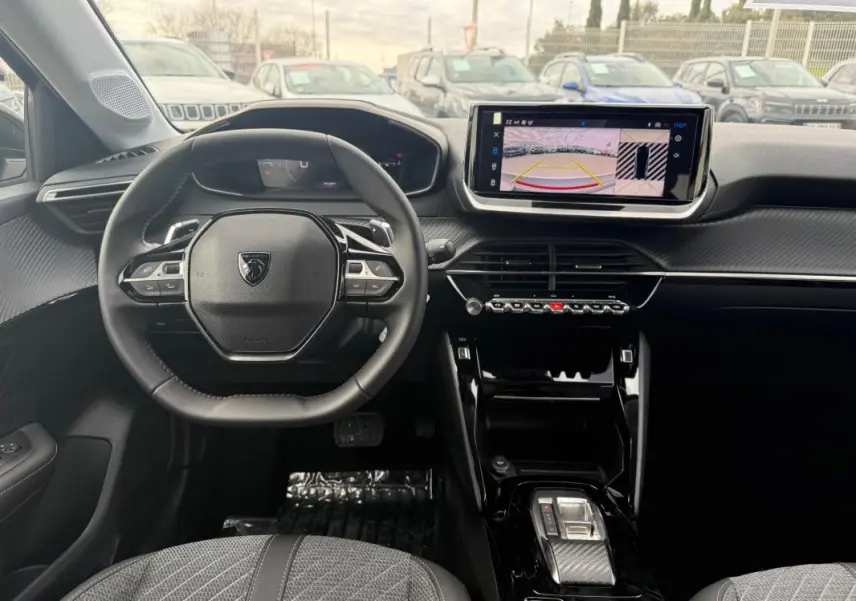 Vue intérieure avant de la Peugeot 208 Hybrid 145 Allure, volant cuir, écran tactile avec caméra de recul, sellerie grise.