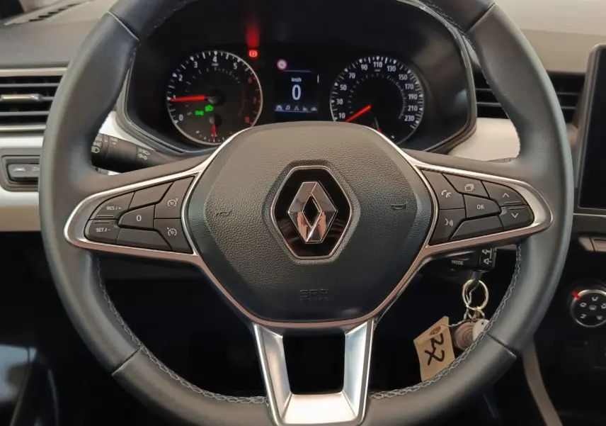 Vue rapprochée du volant cuir multifonctions noir de la Renault Clio Evolution TCe 90 avec tableau de bord en arrière-plan.