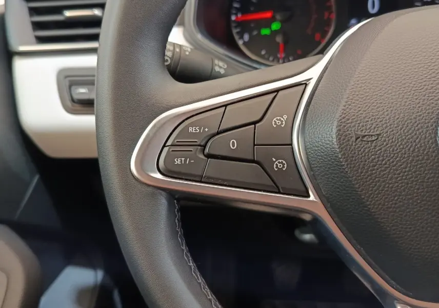 Gros plan sur le volant cuir synthétique noir de la Renault Clio 2023 avec commandes du régulateur de vitesse.