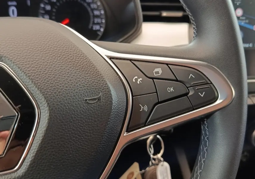 Gros plan sur le volant cuir synthétique multifonctions de la Renault Clio Evolution TCe 90 blanche de 2023.