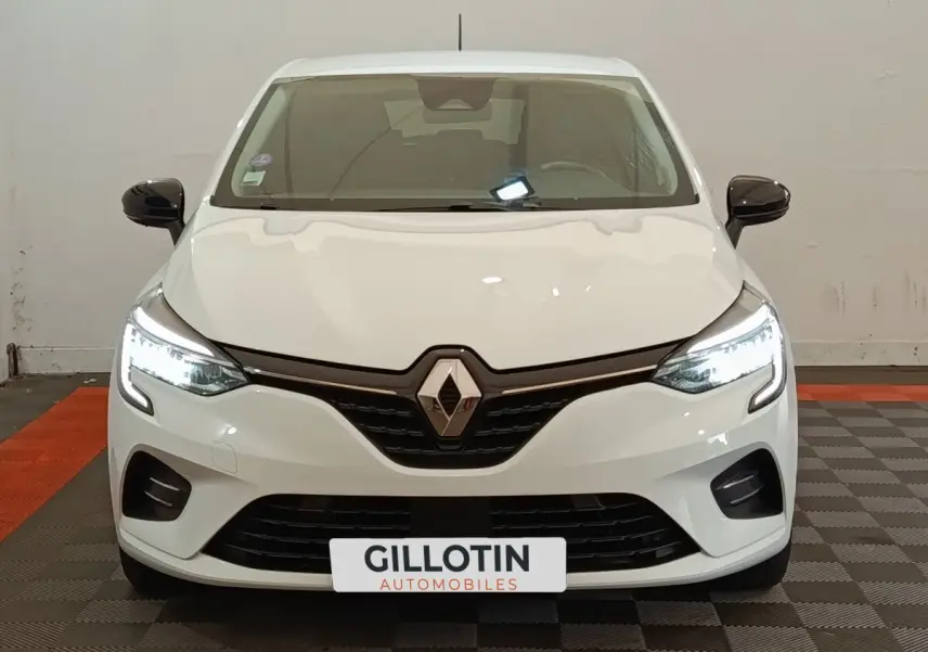 Vue avant d'une Renault Clio Evolution TCe 90 blanche avec phares LED allumés et rétroviseurs noirs.