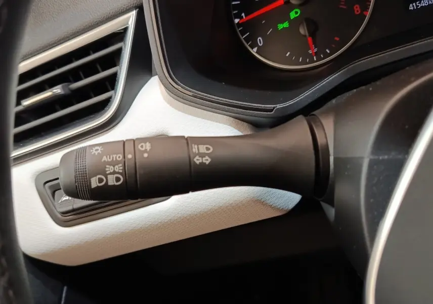 Gros plan sur la commande des phares et clignotants côté gauche du tableau de bord blanc de la Renault Clio Evolution TCe 90.