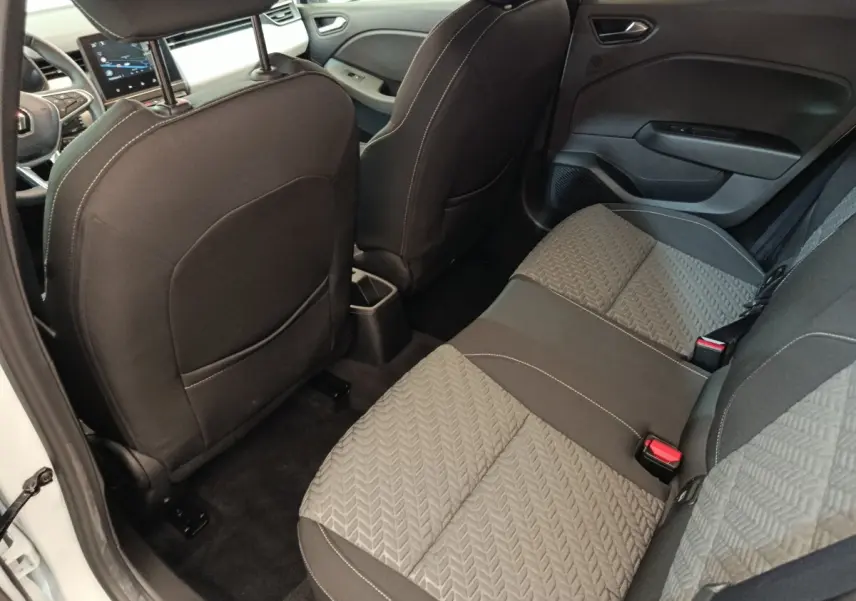Vue intérieure arrière droite de la Renault Clio blanche 2023, sièges tissu gris à motifs et dossier avant noir.