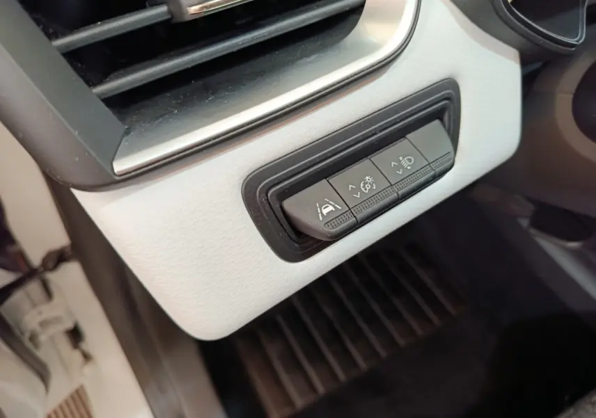 Gros plan sur les commandes d'assistance à la conduite sur tableau de bord blanc de la Renault Clio Evolution TCe 90.