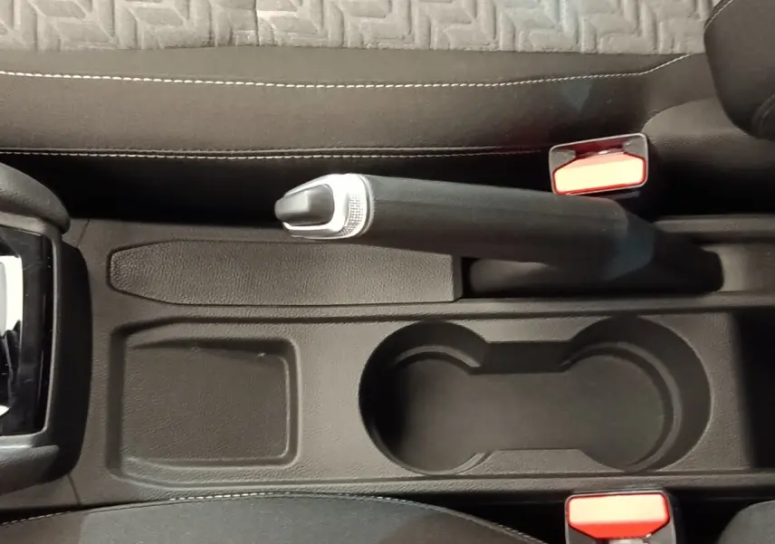 Vue plongeante sur la console centrale noire de la Renault Clio Evolution TCe 90 avec frein à main et porte-gobelets.