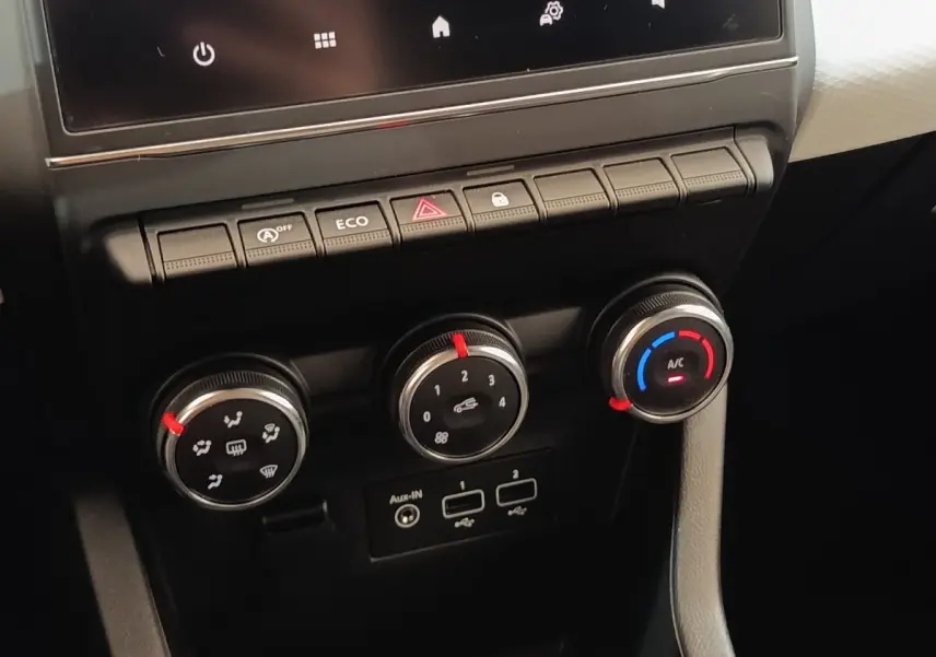 Gros plan sur les commandes de climatisation et boutons de fonction du tableau de bord de la Renault Clio blanche 2023.