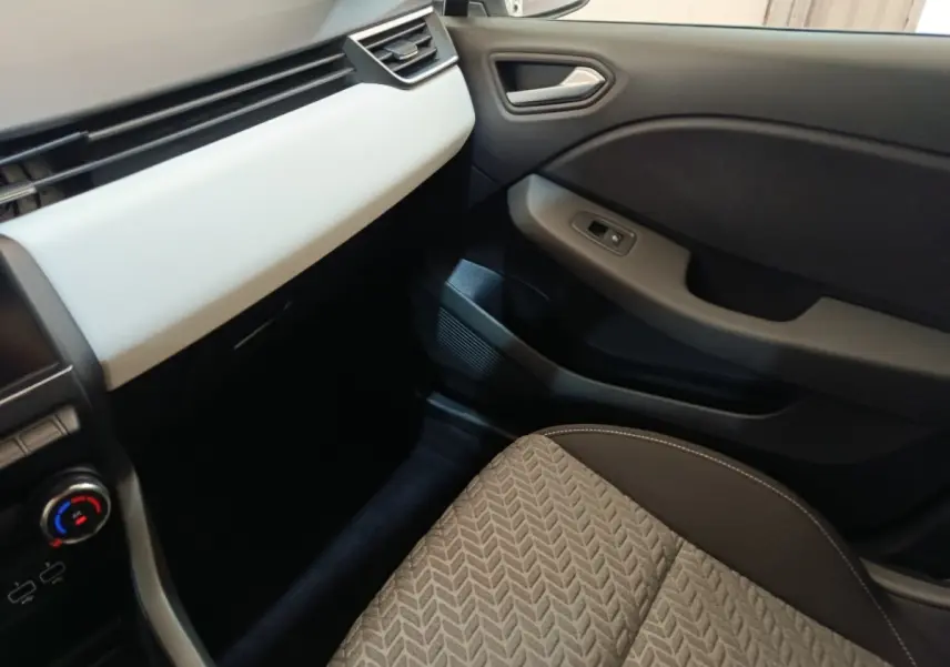 Vue intérieure côté passager avant de la Renault Clio Evolution TCe 90 2023, siège tissu gris et tableau de bord clair.