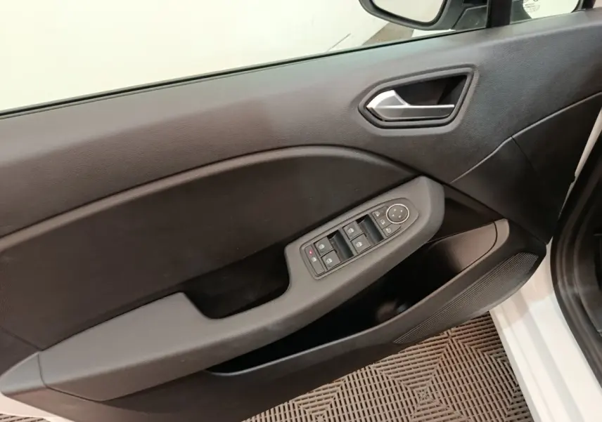 Vue intérieure du panneau de porte avant gauche de la Renault Clio blanche, avec commandes électriques des vitres et rétroviseurs.