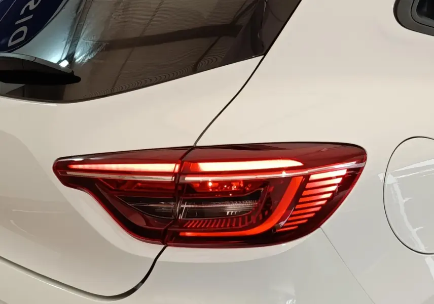 Gros plan sur le feu arrière droit rouge allumé d’une Renault Clio blanche Evolution TCe 90 de 2023.