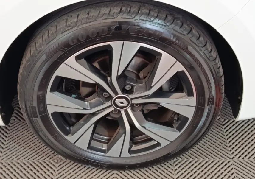 Gros plan sur la jante alliage noire et argentée d'une Renault Clio blanche, avec pneu Goodyear visible.