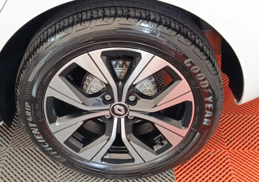 Gros plan sur la roue avant droite d’une Renault Clio blanche, jante alliage bicolore et pneu Goodyear.