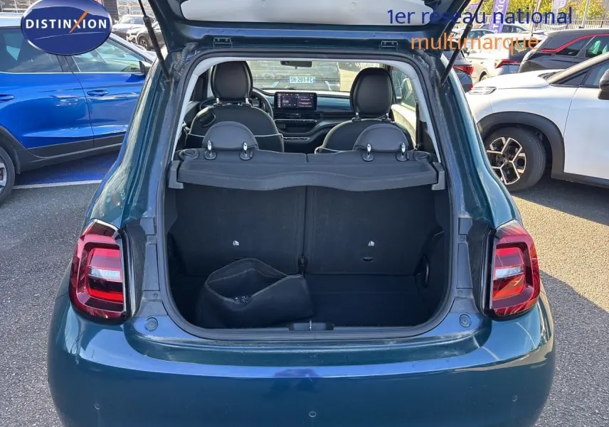 Vue arrière d'une FIAT 500 électrique 2023 vert océan métal avec coffre ouvert montrant l'intérieur et les sièges noirs.