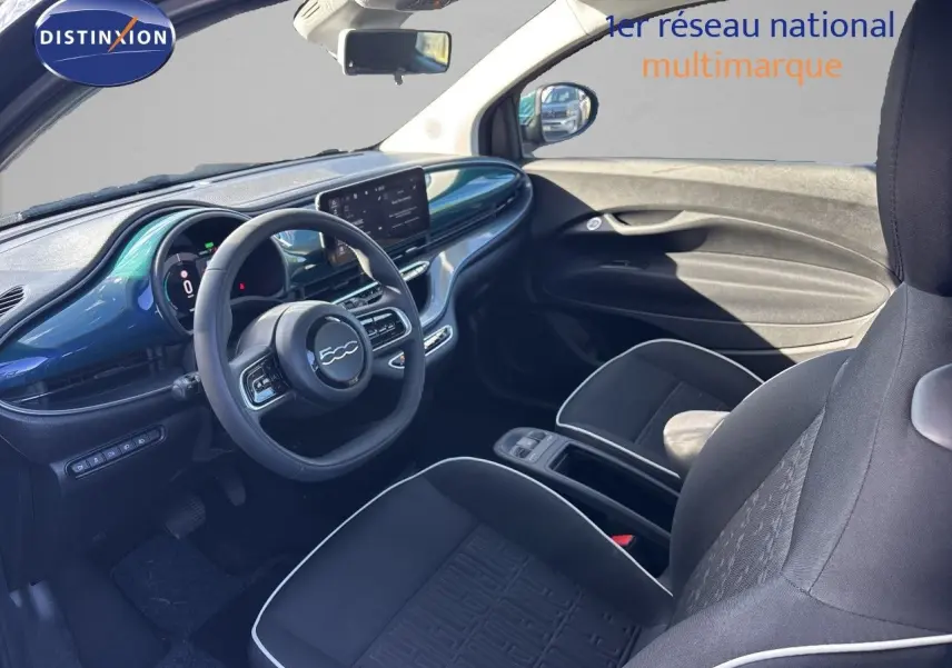 Vue intérieure côté conducteur de la Fiat 500 électrique 2023 avec tableau de bord vert océan métallisé et sièges noirs.