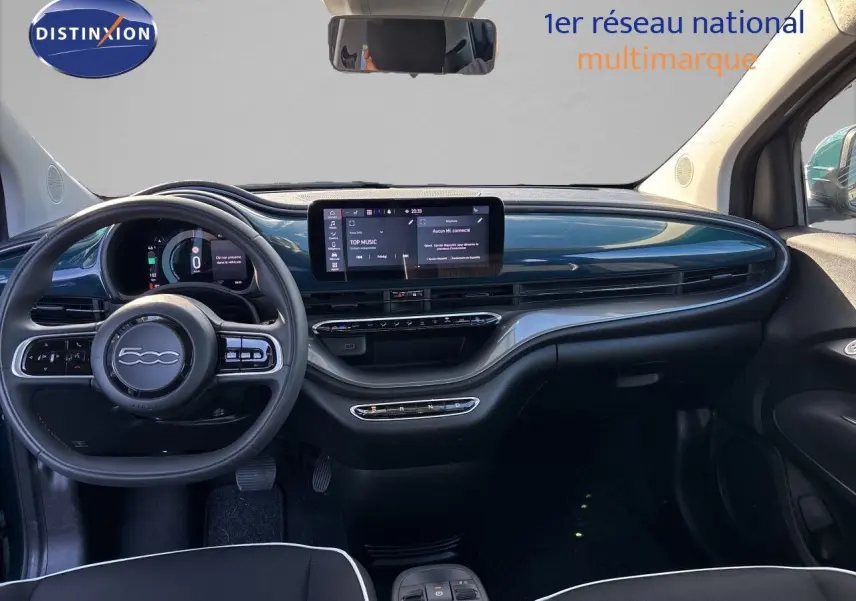 Intérieur de la Fiat 500 électrique 2023 vu de face, tableau de bord vert océan métallisé avec écran tactile central.