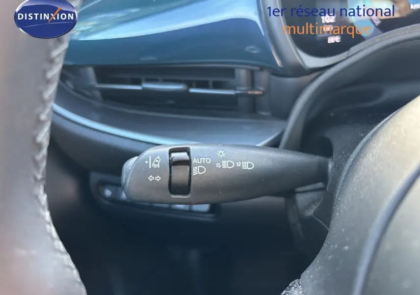 Gros plan sur la commande des feux au volant d’une FIAT 500 électrique 2023, intérieur noir.