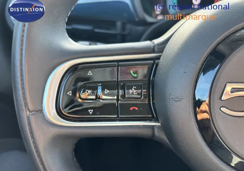 Gros plan sur les commandes gauche du volant noir de la FIAT 500 électrique 2023, mettant en valeur les boutons multifonctions.