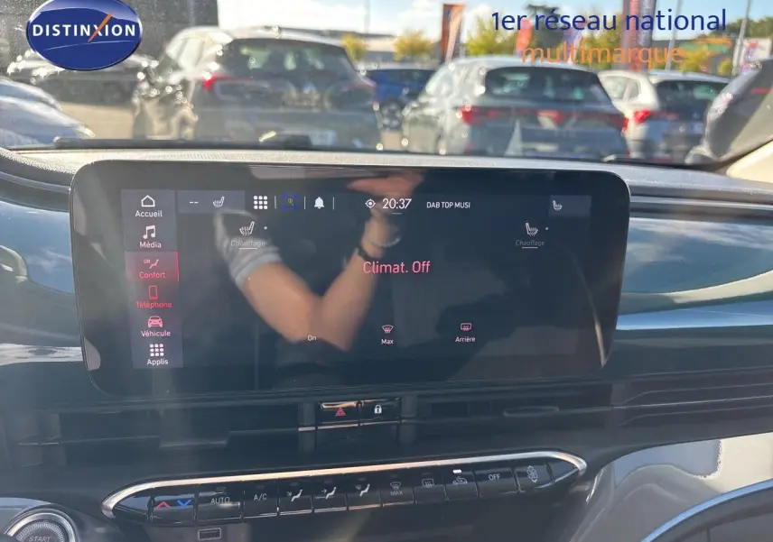Vue intérieure centrée sur l'écran tactile du tableau de bord de la FIAT 500 électrique, avec reflet et commandes climatisation visibles.