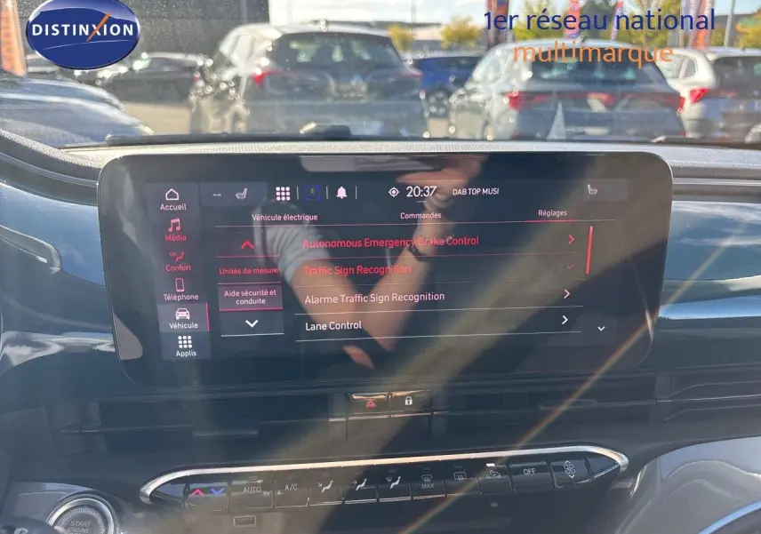 Écran tactile central de la Fiat 500 électrique 2023, vue intérieure avant avec reflets et commandes climatisation visibles.