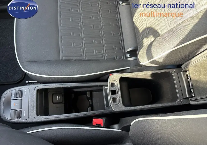 Vue rapprochée de la console centrale et des sièges en tissu noir avec surpiqûres blanches d'une Fiat 500 électrique 2023.