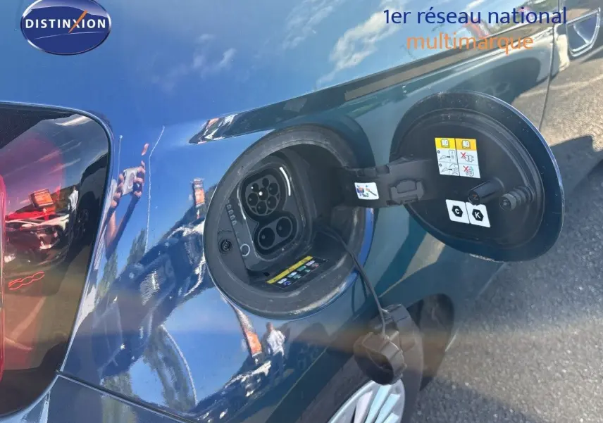 Prise de recharge électrique ouverte côté gauche d’une FIAT 500 Electrique 2023 vert océan métal, avec câble de charge visible.