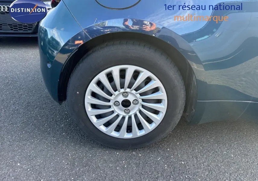 Gros plan sur la roue arrière droite d'une FIAT 500 électrique 2023 vert océan métal avec jante argentée multibranches.