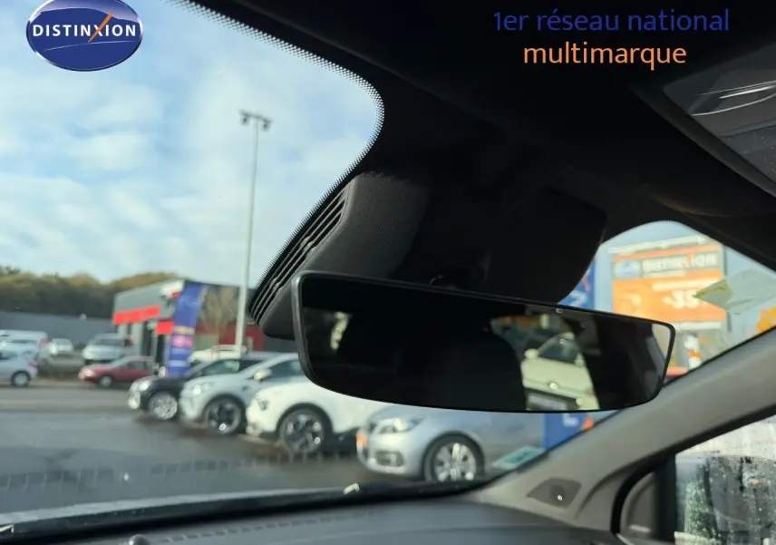 Vue intérieure du rétroviseur central d'un MG3 1.5 Hybrid 2024, avec aperçu flou du parking extérieur.